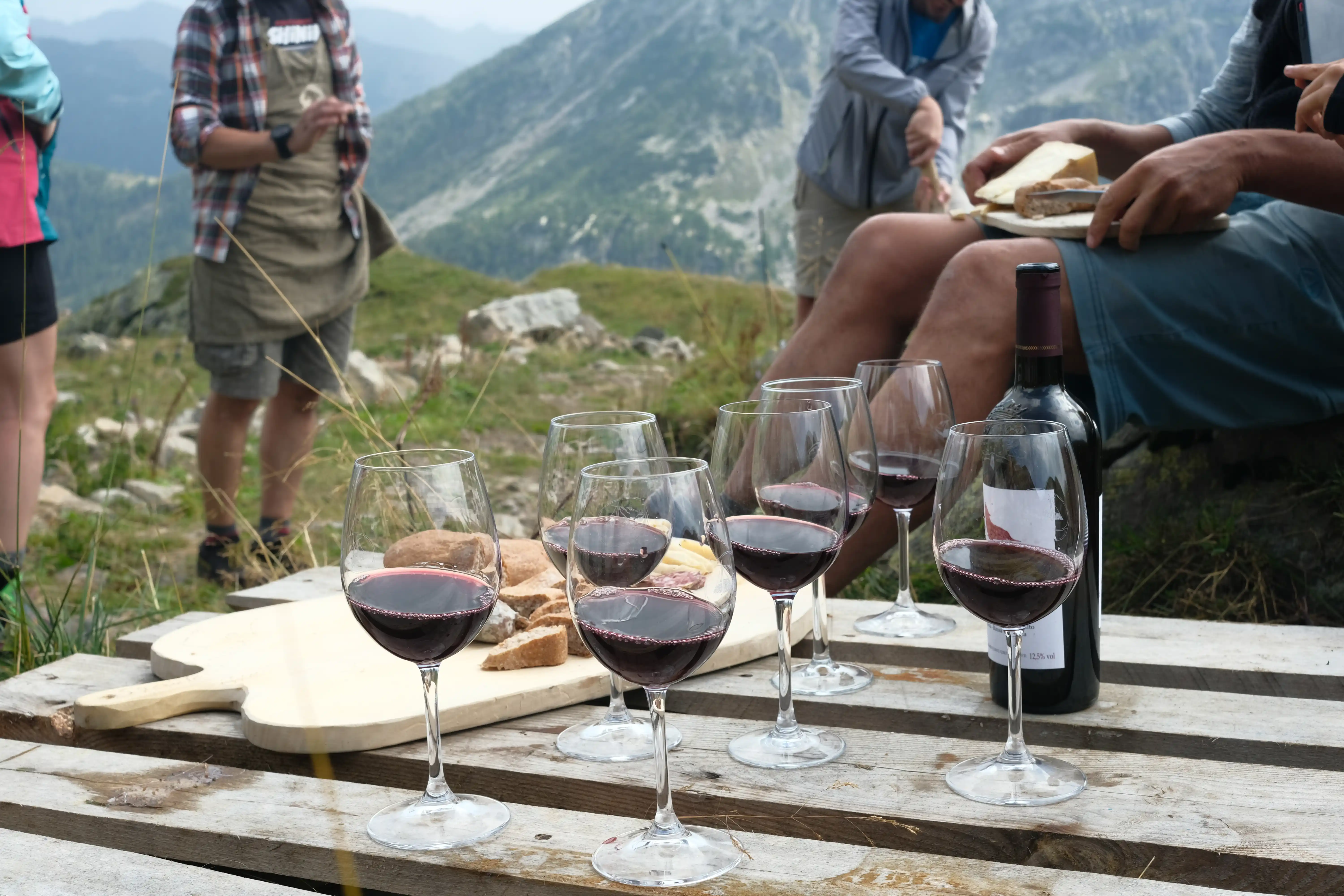 Person on mountain peak with wine and cheese